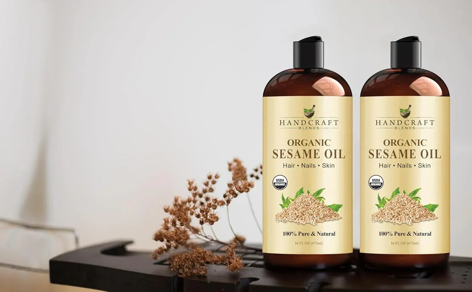 Two bottles of organic sesame oil for hair, nails, and skin on a spa-like table.
