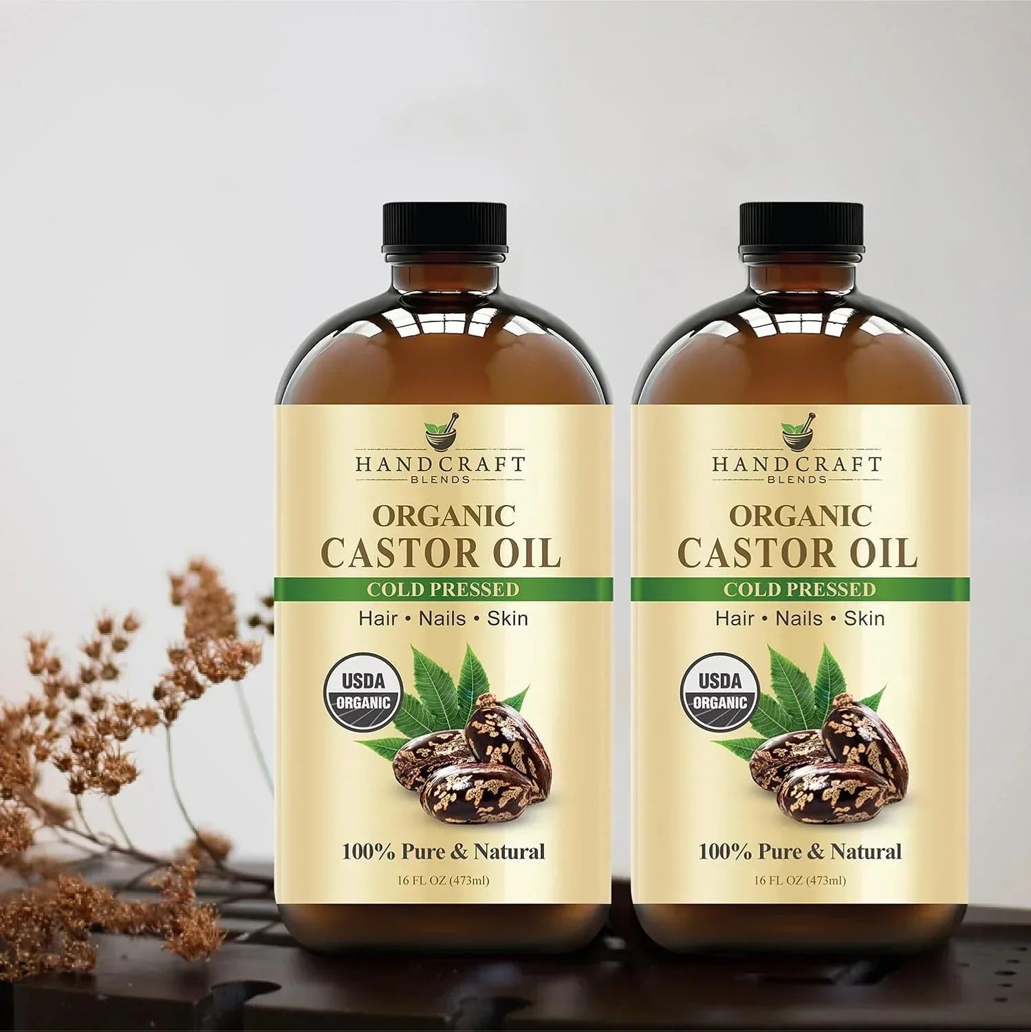 Two bottles of organic cold pressed castor oil for hair, nails, and skin on a table.