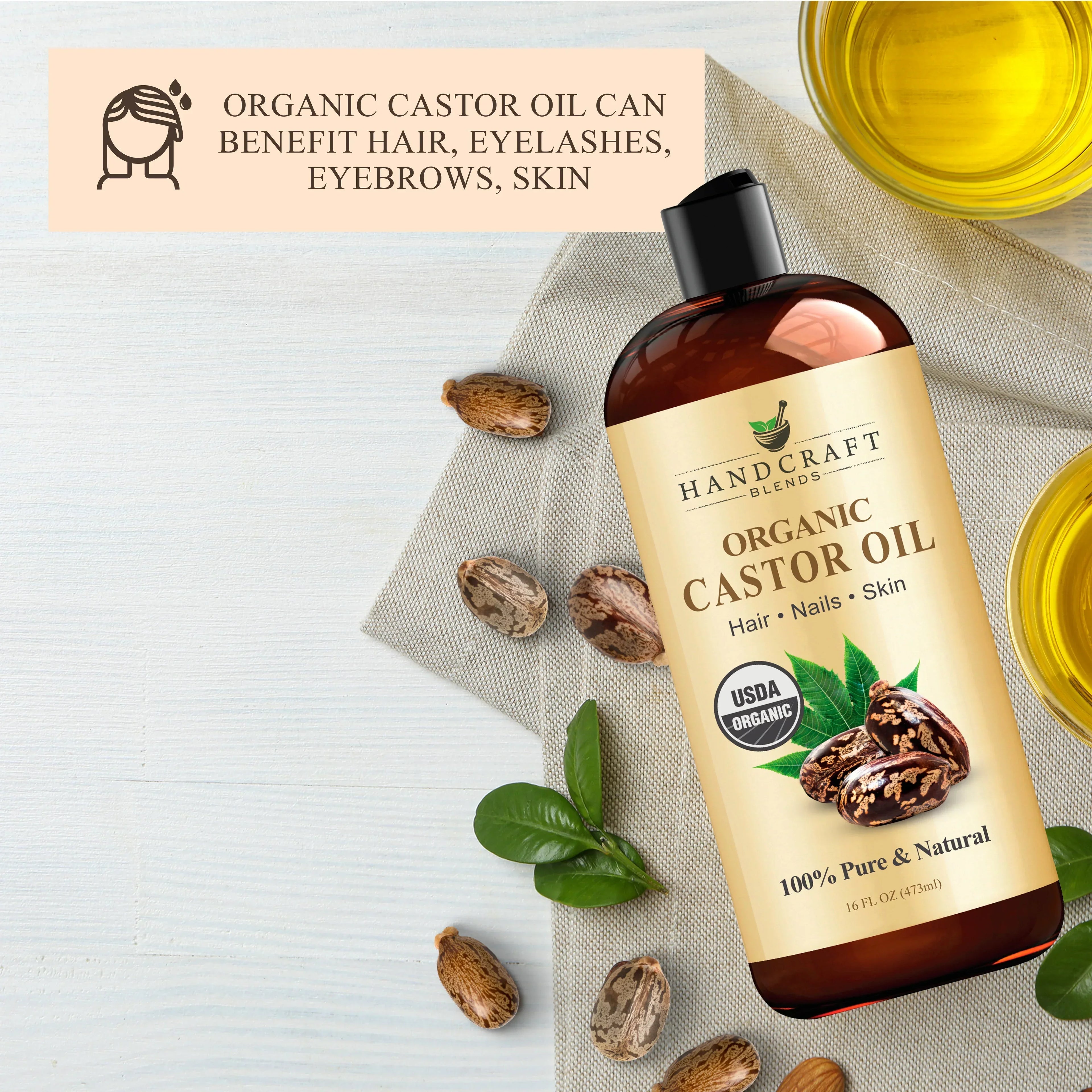 Organic castor oil bottle with castor seeds, leaves, and oil on white background