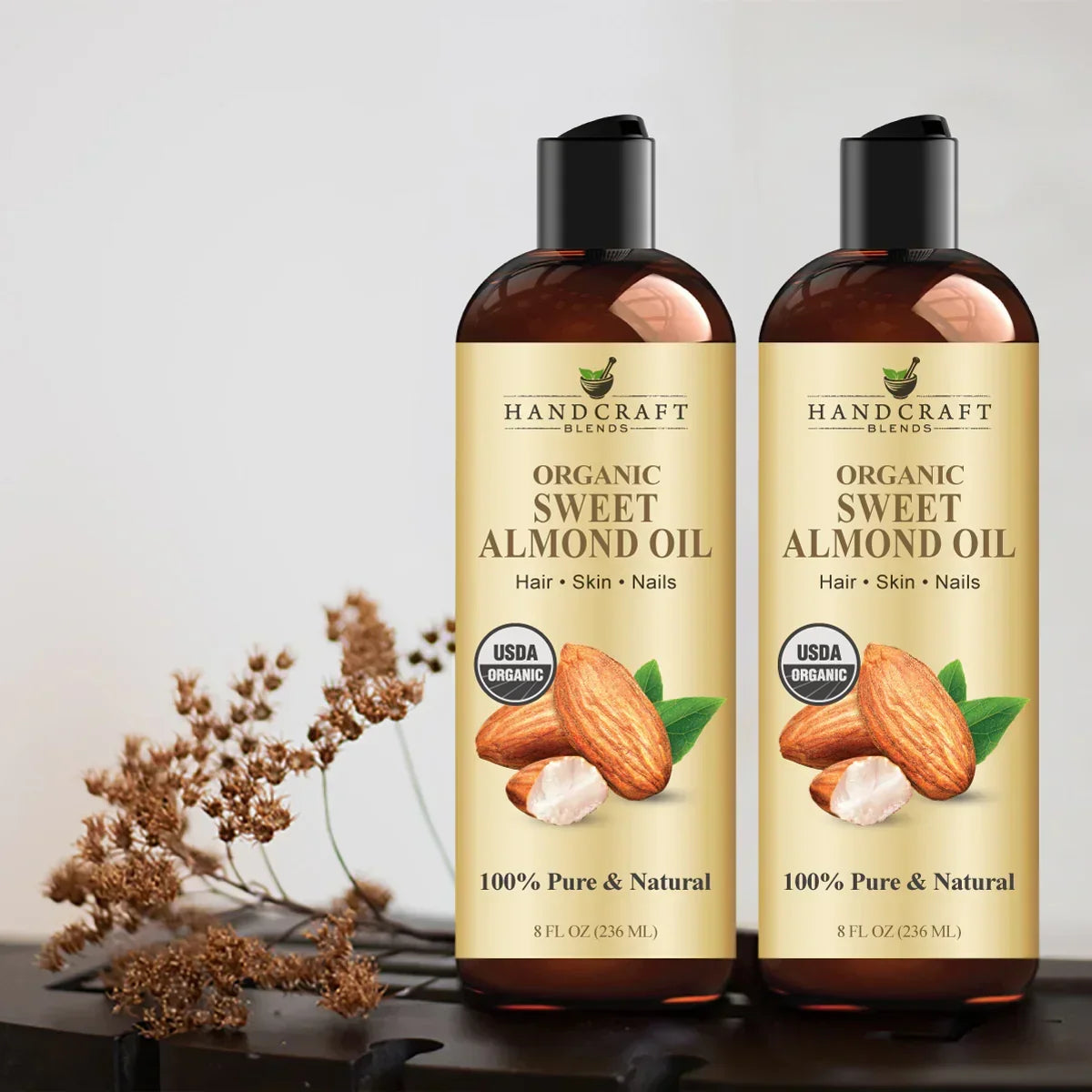 Two bottles of organic sweet almond oil for hair, skin, and nails on a neutral background.