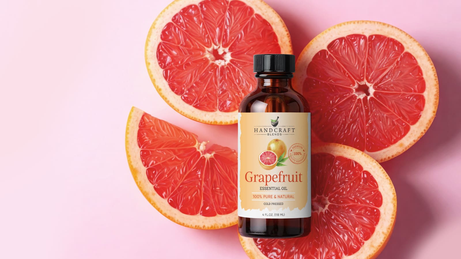 Grapefruit essential oil bottle with fresh grapefruit slices on a pink background.