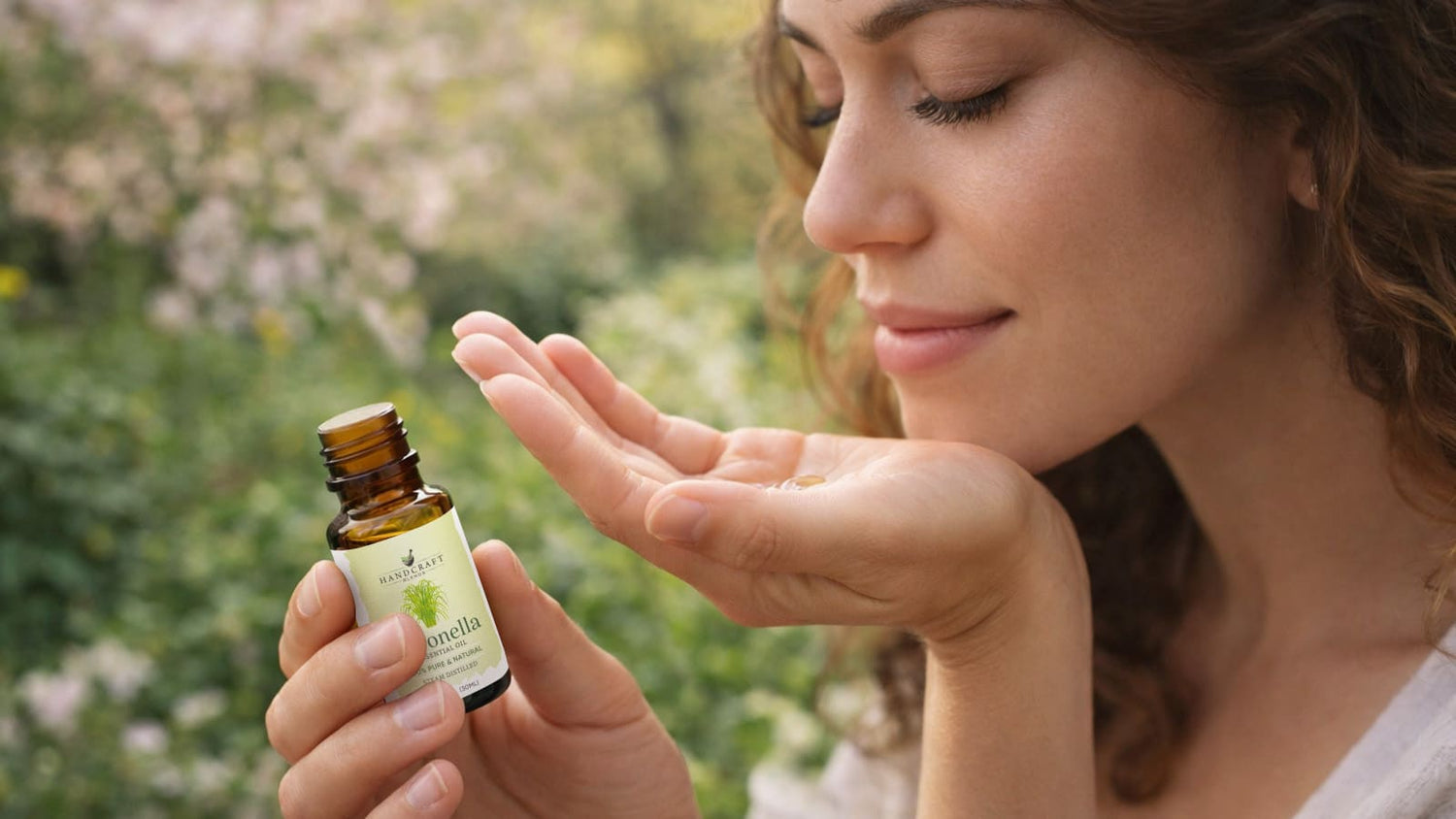 Woman enjoying citronella essential oil outdoors, holding amber glass bottle and inhaling scent