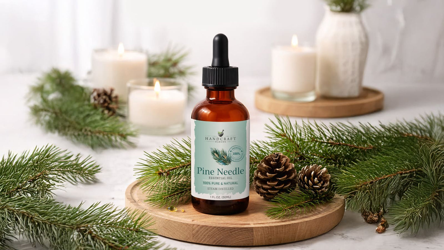Pine needle essential oil bottle with dropper, pine branches, pinecones, and candles on a table.