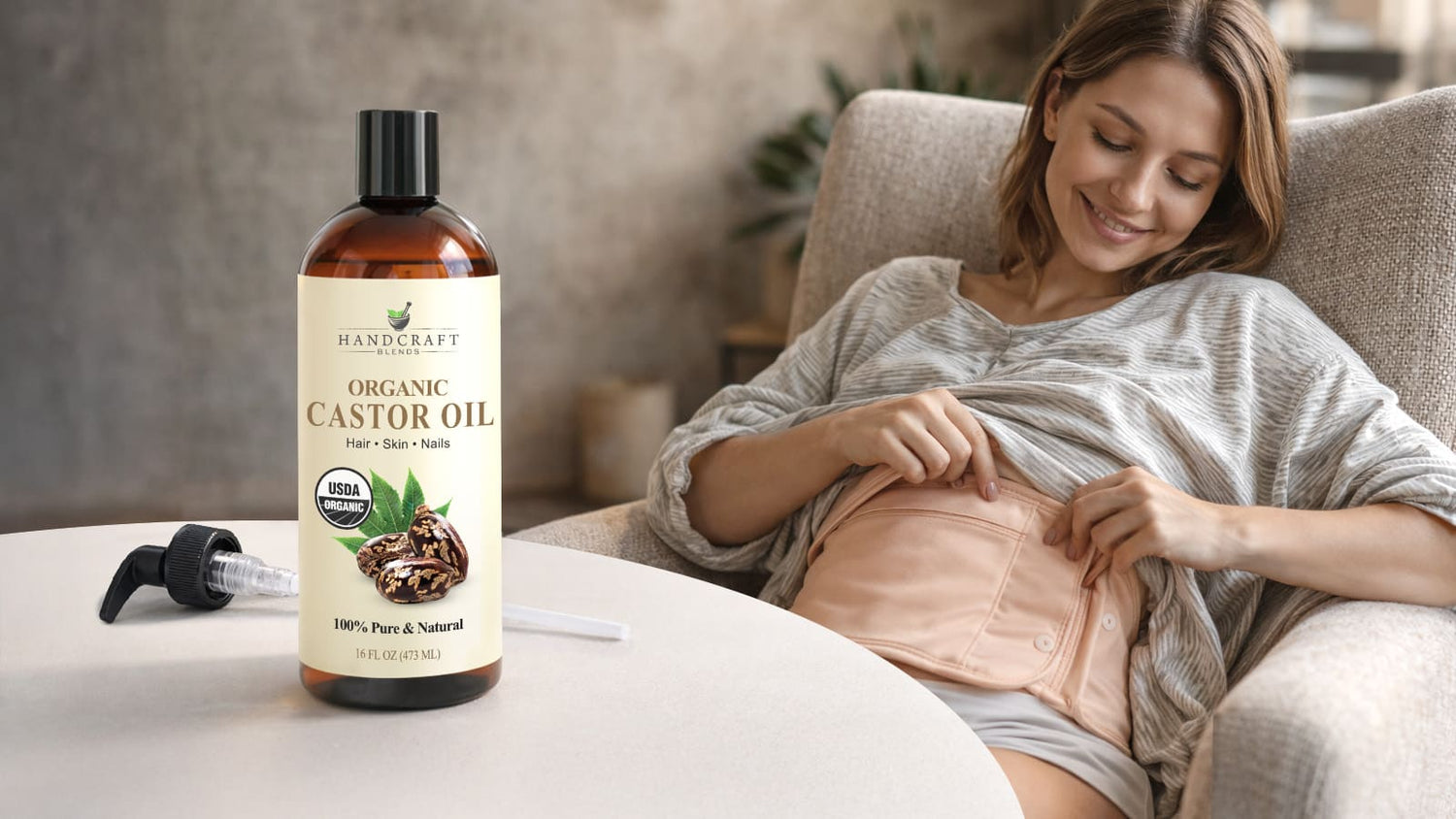 Woman using a beige castor oil wrap on abdomen, organic castor oil bottle in foreground.