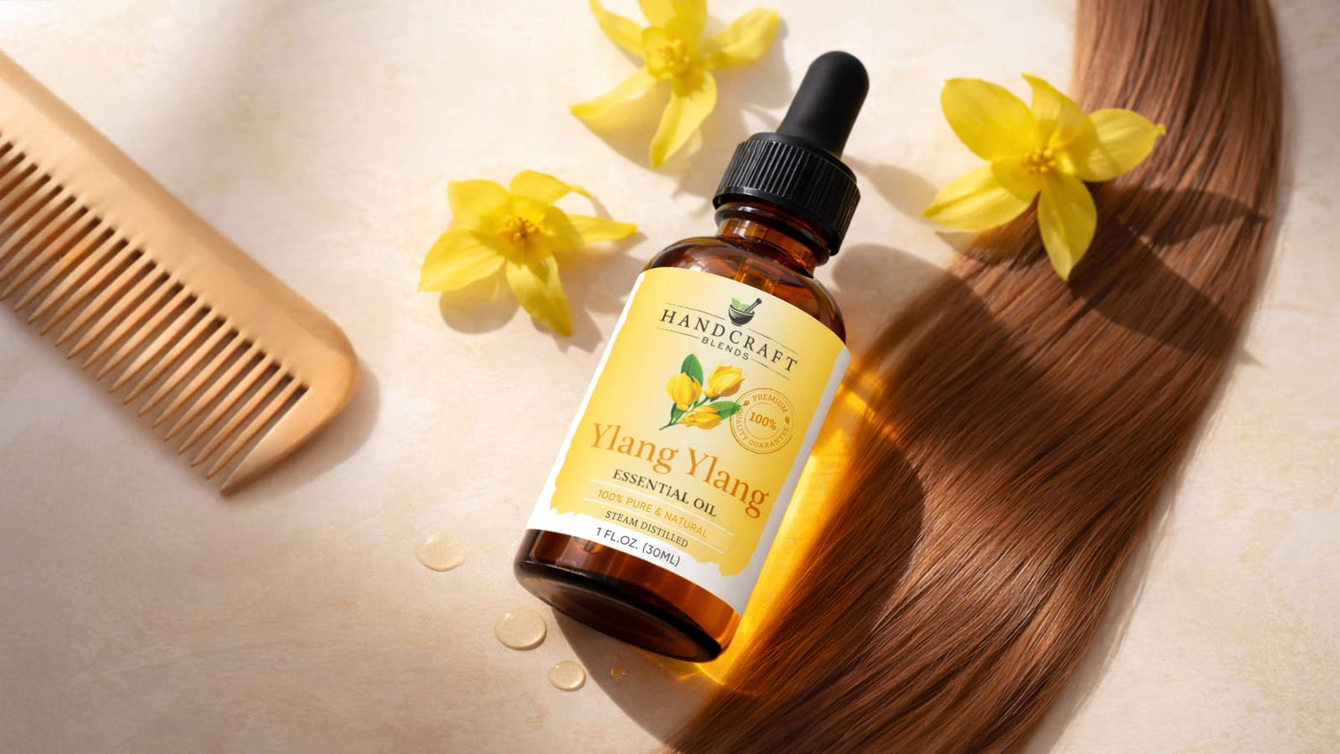Ylang ylang essential oil bottle with yellow flowers, wooden comb, and brown hair strand