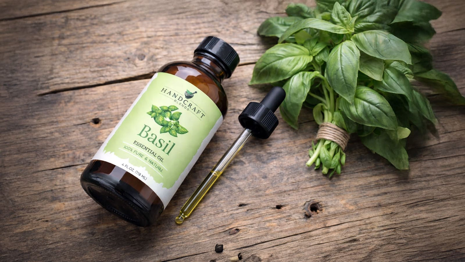 Basil essential oil bottle with dropper and fresh basil leaves on rustic wooden table