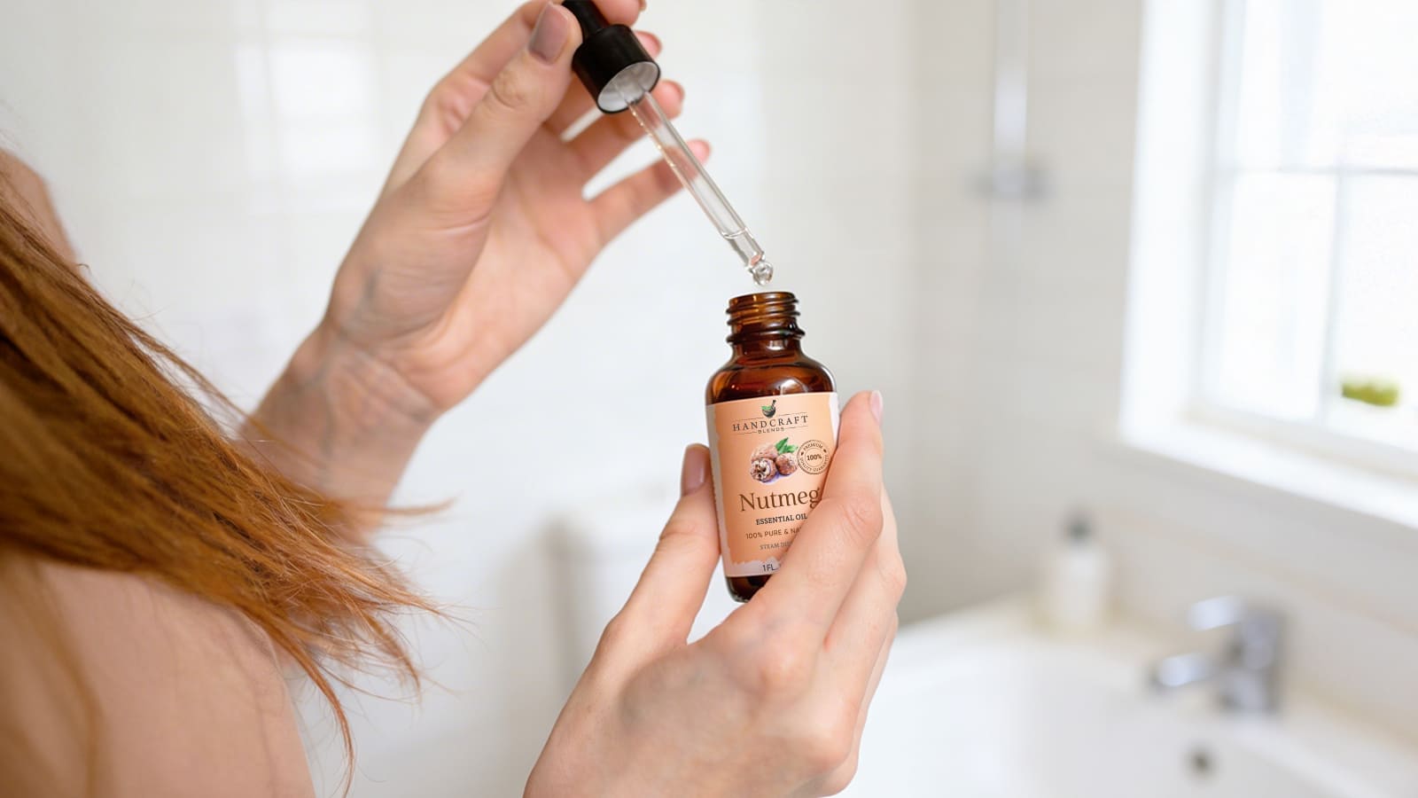 Woman using dropper with nutmeg essential oil bottle in a bright bathroom