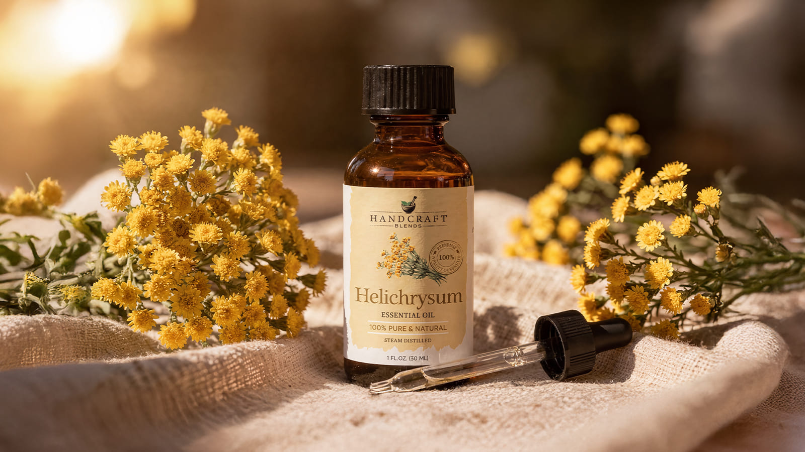 Helichrysum essential oil bottle with dropper and yellow flowers on fabric, golden sunlight