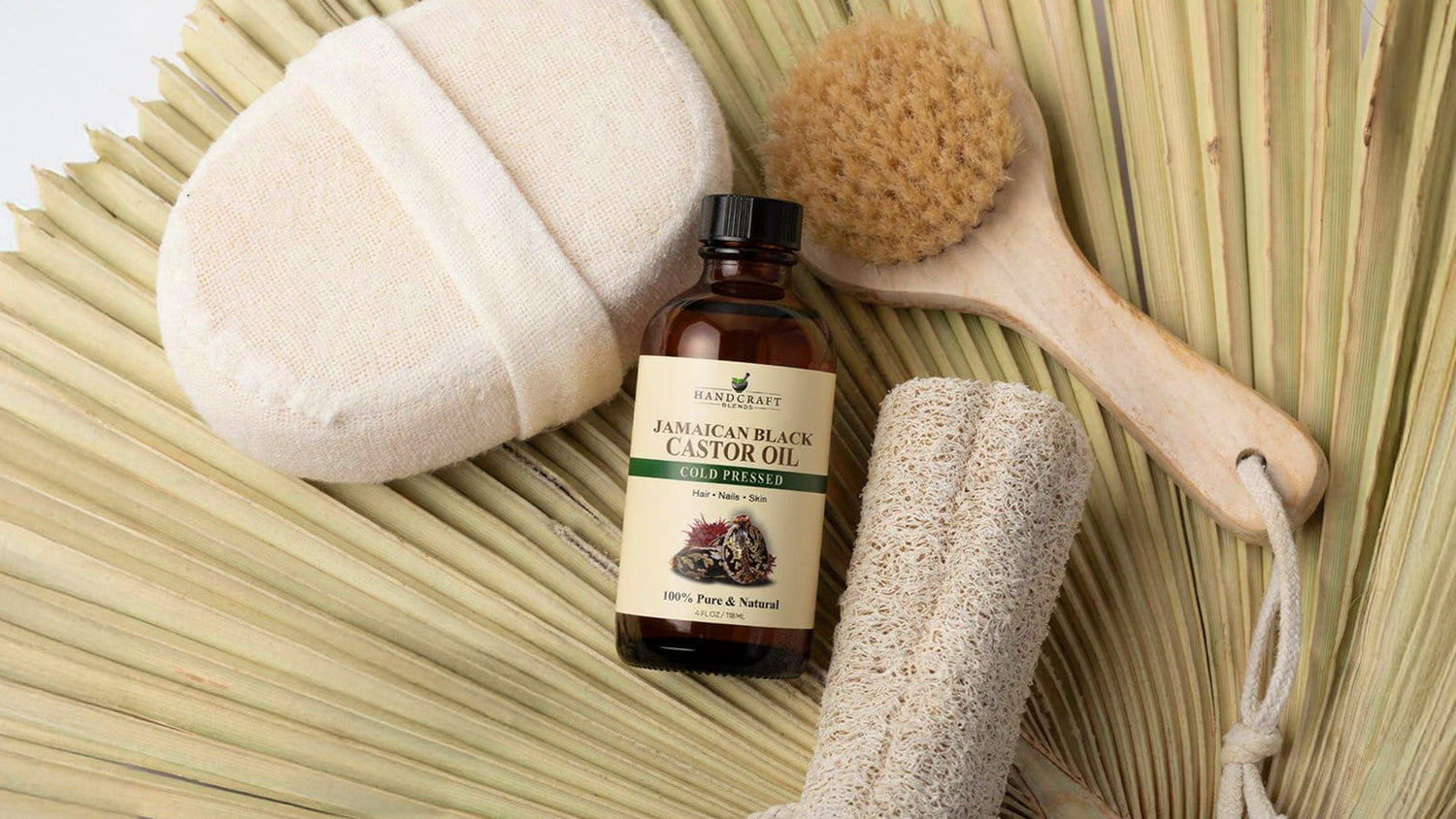 Jamaican Black Castor Oil bottle with natural bath accessories on palm leaf