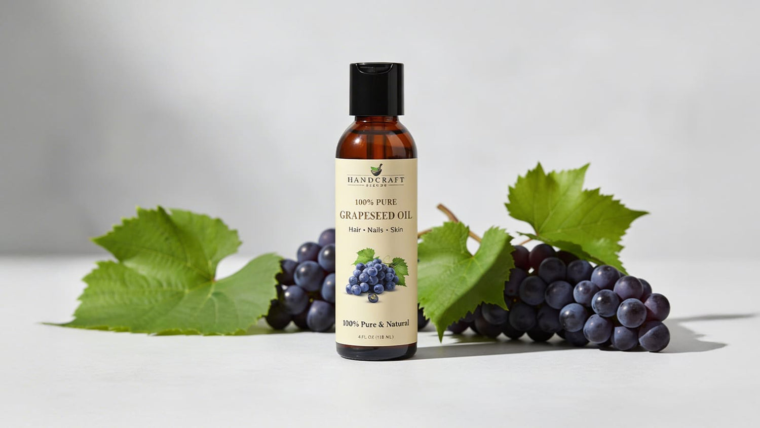 Grapeseed oil bottle with fresh grapes and green leaves on white background