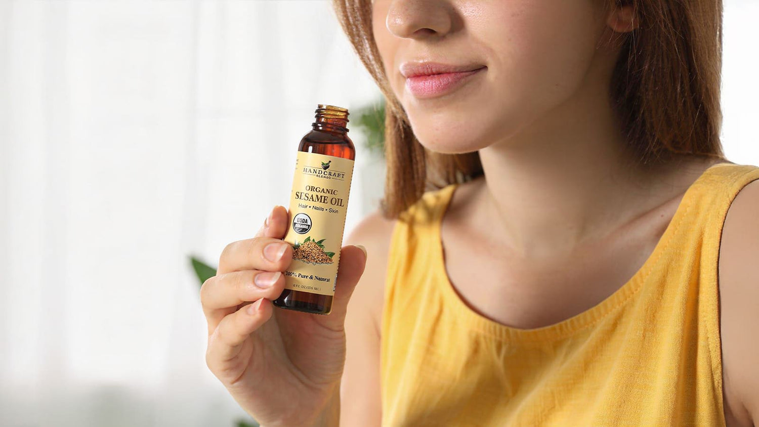 Woman holding bottle of organic sesame oil for hair, nail, and skin care