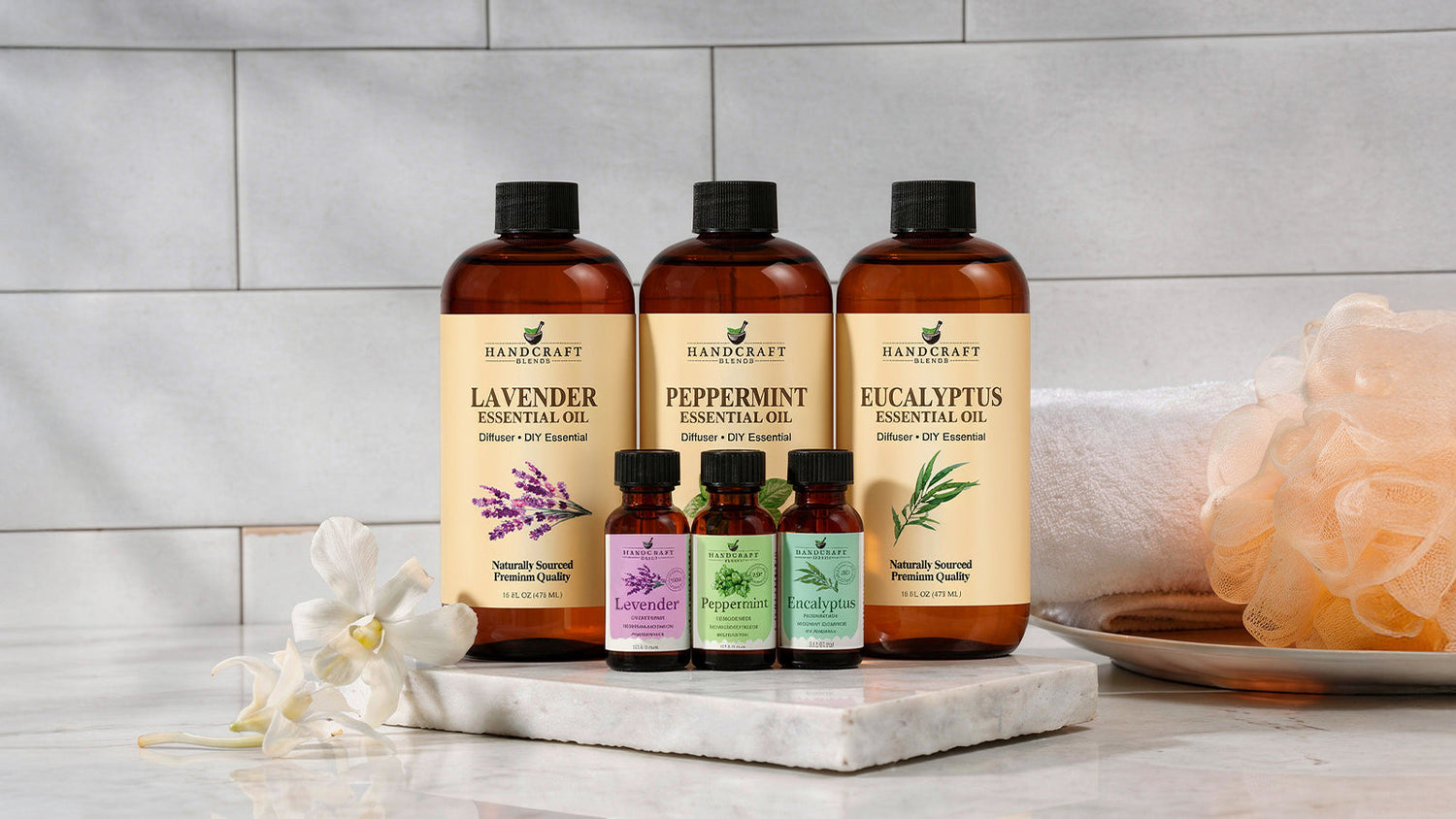 Large and small bottles of lavender, peppermint, and eucalyptus essential oils on a marble surface.