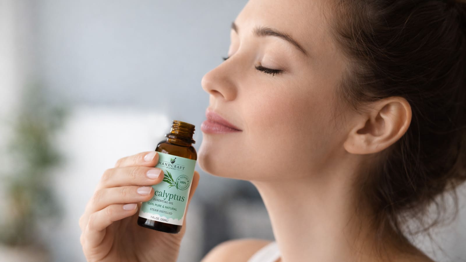 Woman enjoying eucalyptus essential oil aroma from amber bottle