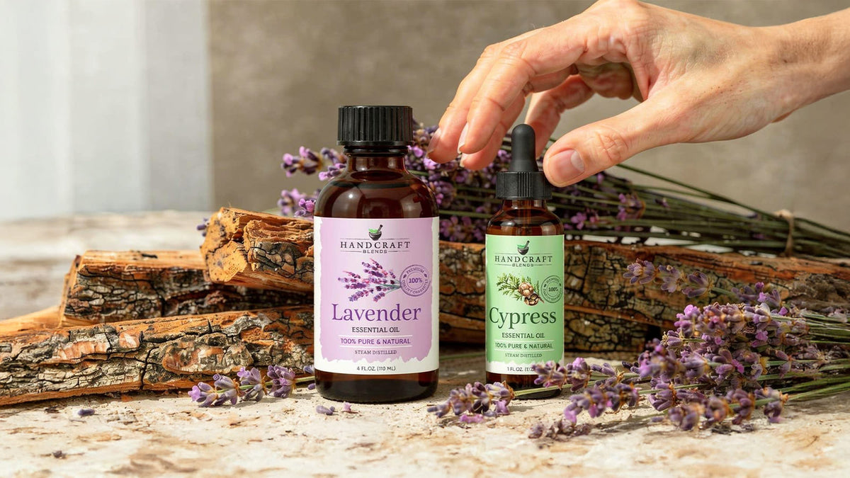 Jasmine and sandalwood essential oil bottles on a pale wood surface with a single white flower